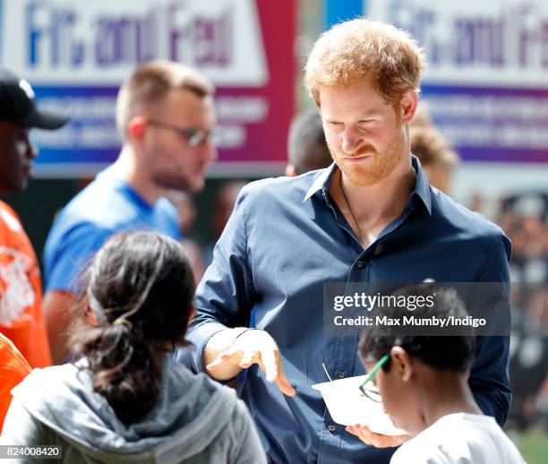 Prince Harry serves lunch to children taking part in a StreetGames 'Fit and Fed' summer holiday activity session in Central Park, East Ham on July...