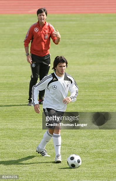 Serdar Tasci of Germany runs with the ball ball while coach Joachim Loew watches him during a training session of the German national football team...