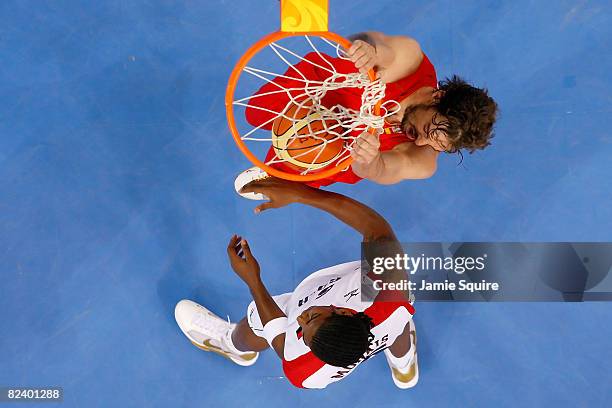 Pau Gasol of Spain dunks over the defense of Carlos Morais of Angola during the men's basketball preliminaries at the Wukesong Indoor Stadium on Day...
