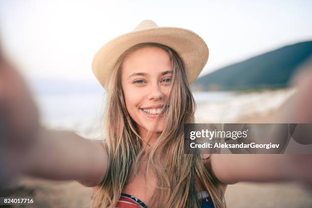 leende ung flicka med stråhatt tar selfie i sommar på stranden - beach selfie bildbanksfoton och bilder