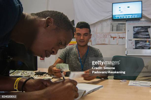 Staff check the details of an asylum seeker and then they give them their daily money allowance on July 27, 2017 in Bologna, Italy. In an effort to...