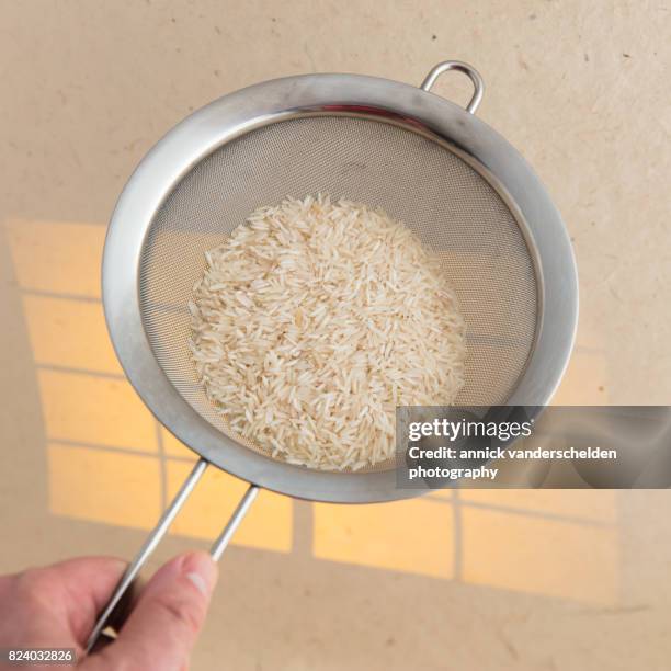 basmati rice in a kitchen sieve. - belgium india stock pictures, royalty-free photos & images