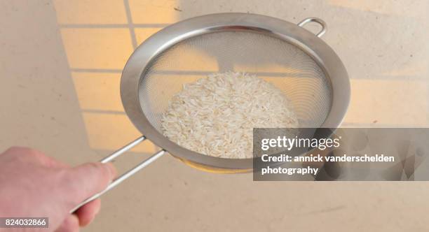 basmati rice in a kitchen sieve. - belgium india stock pictures, royalty-free photos & images