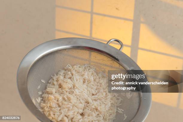 washed basmati rice in a kitchen sieve. - belgium india stock pictures, royalty-free photos & images