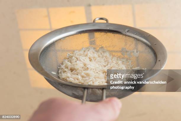 washed basmati rice in a kitchen sieve. - belgium india stock pictures, royalty-free photos & images