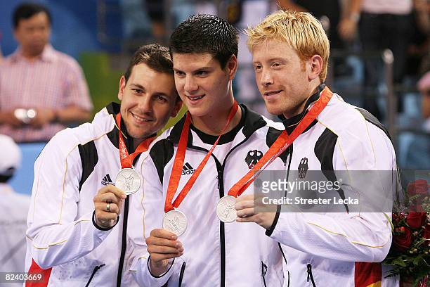 Timo Boll, Dimitrij Ovtcharov and Christian Suess of Germany celebrate their silver medal in the Men's Team Contest against China at the Peking...