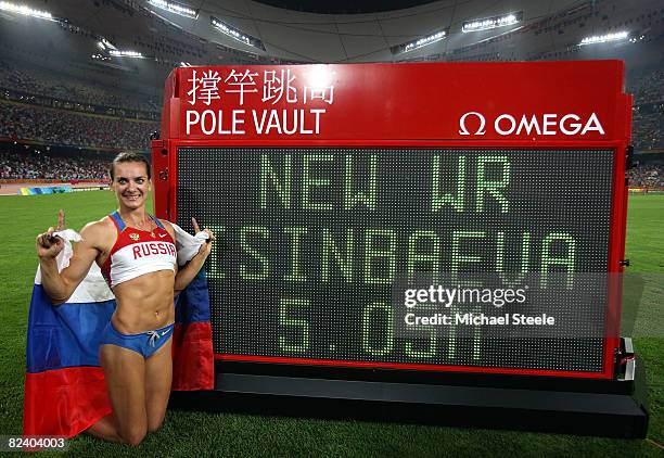 Elena Isinbaeva of Russia poses next to the scoreboard with her new World Record of 5.05 in the Women's Pole Vault Final at the National Stadium on...