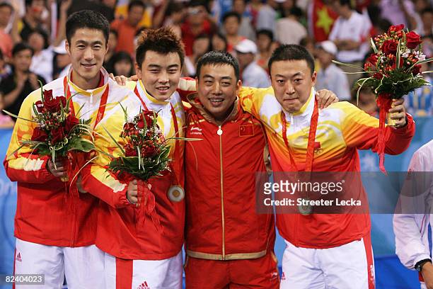 Ma Lin, Wang Hao and Wang Liqin and their coach Qi Chen of China celebrate their gold medal in the Men's Team Contest at the Peking University...
