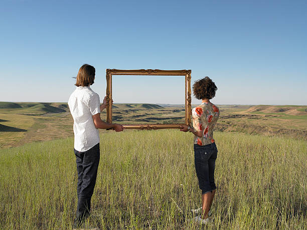 man and woman holding frame in open land