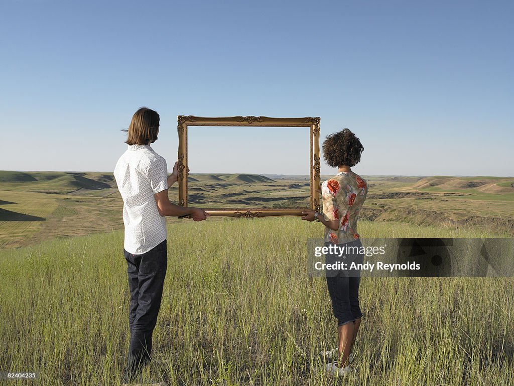 Man and woman holding frame in open land