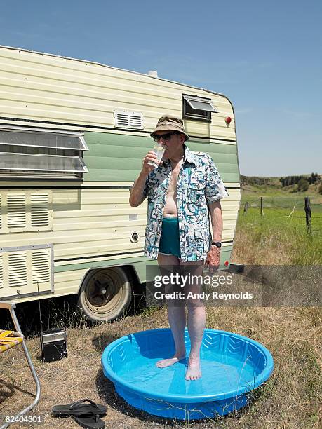 man standing in wading pool, drinking  - bath relaxation stock pictures, royalty-free photos & images