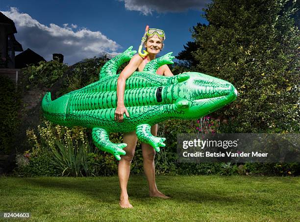 mature woman holds inflatable crocodile in garden. - dykmask bildbanksfoton och bilder