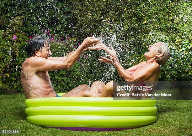 mature couple splashing in paddlingpool. - couple de vieux drole photos et images de collection