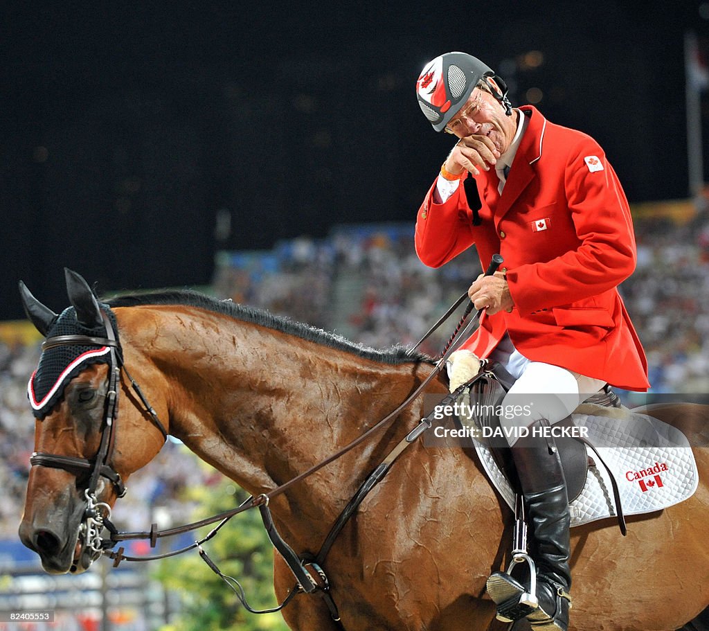 Ian Millar of Canada reacts after riding