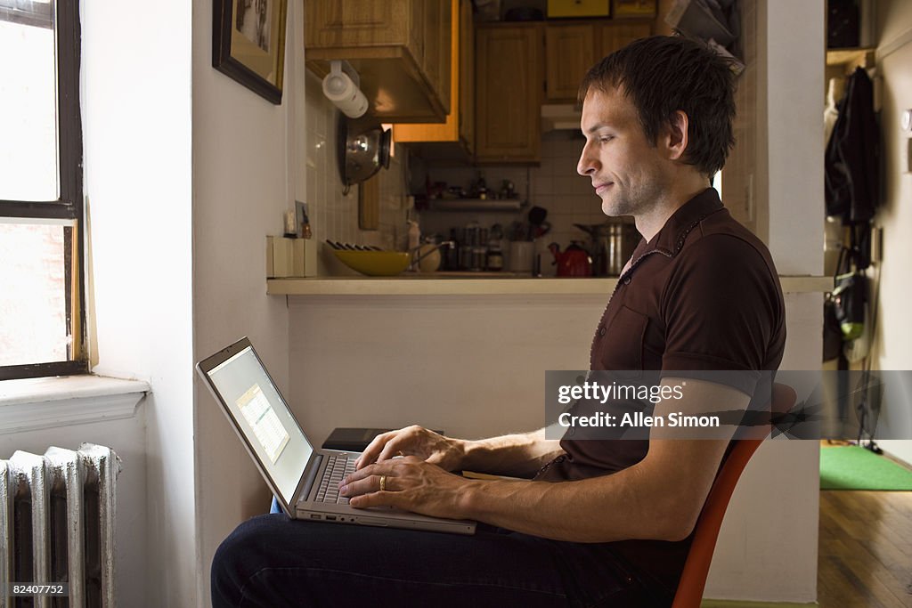 Man using laptop in small studio apartment