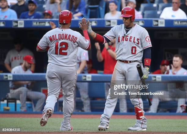 Martin Maldonado of the Los Angeles Angels of Anaheim is congratulated by Yunel Escobar after scoring a run in the second inning during MLB game...