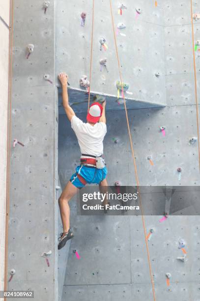 giovane si arrampica su parete rocciosa interna - messa in sicurezza foto e immagini stock