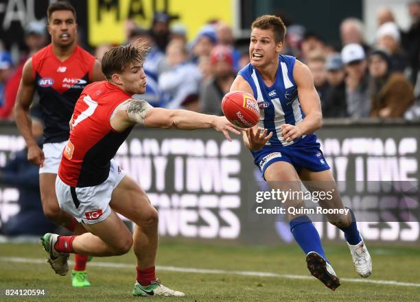 Andrew Swallow of the Kangaroos handballs whilst being tackled by Jack Viney of the Demons during the round 19 AFL match between the North Melbourne...