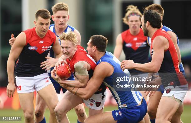 Clayton Oliver of the Demons is tackled by Braydon Preuss of the Kangaroos during the round 19 AFL match between the North Melbourne Kangaroos and...