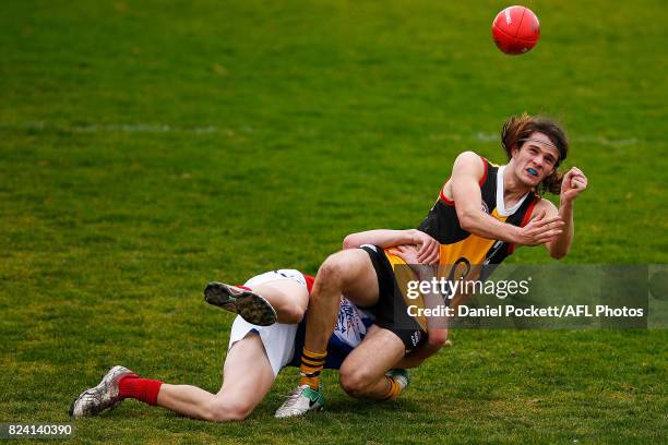 Hunter Clark of the Stingrays handpasses the ball whilst being tackled by Bailey Beck of the Power during the round 14 TAC Cup match between...