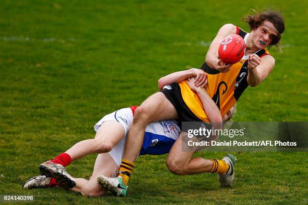 Hunter Clark of the Stingrays handpasses the ball whilst being tackled by Bailey Beck of the Power during the round 14 TAC Cup match between...