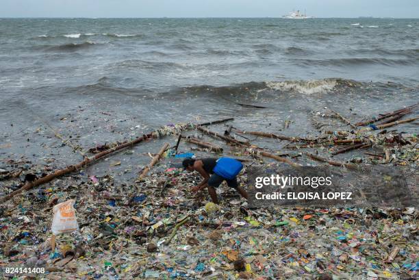 Man picks up garbage washed ashore at Manila Bay on July 29, 2017 after Typhoon Nesat hit the Philippines.