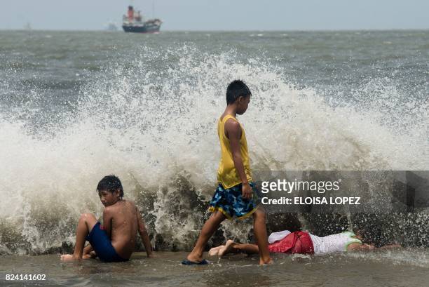 Children play at Manila Bay in Navotas City on July 29 amidst strong waves caused by Typhoon Nesat.