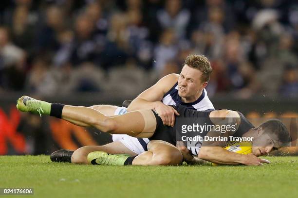 Mitch Duncan of the Cats tackles Marc Murphy of the Blues during the round 19 AFL match between the Carlton Blues and the Geelong Cats at Etihad...