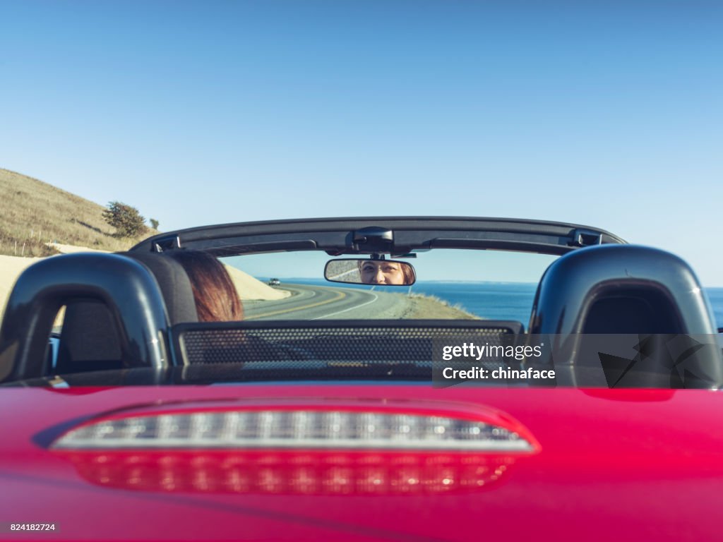 Woman driving convertible at coast highway