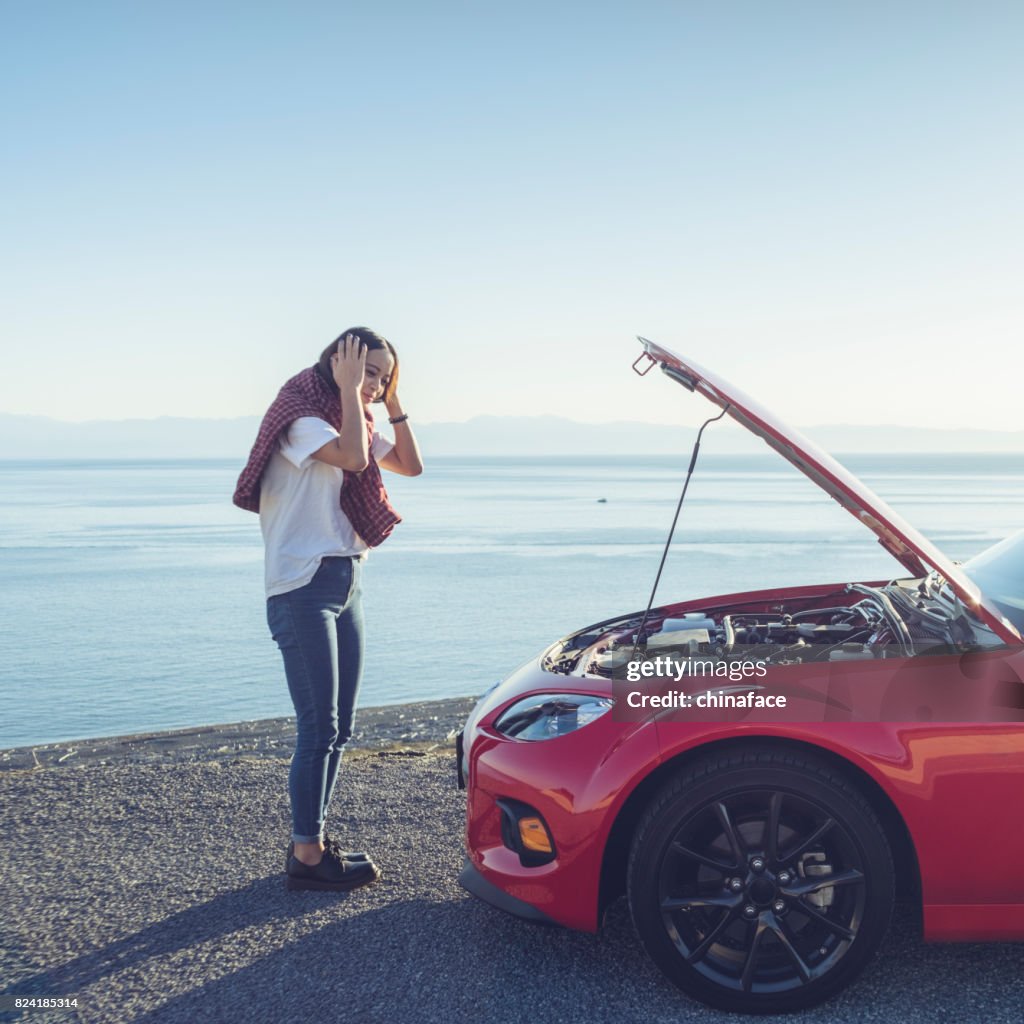 Woman stand by the broken car