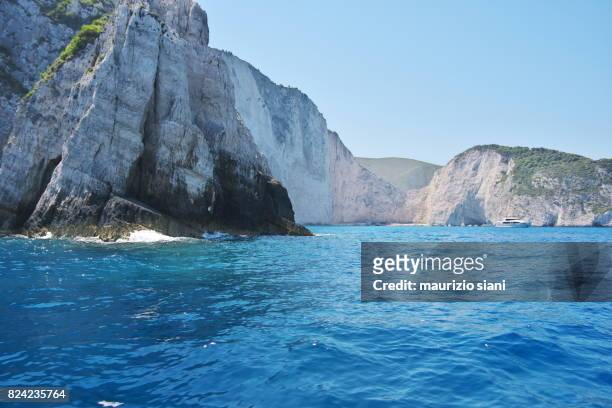 caves by blue sea against sky and famous navagio shipwreck beach. zakynthos, greece - agios georgios church stock pictures, royalty-free photos & images