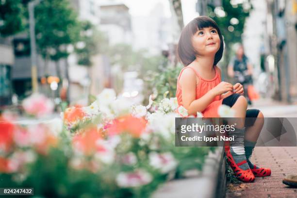 beautiful mixed race little girl sitting on a pedestrian path - toddler girl dress stock pictures, royalty-free photos & images