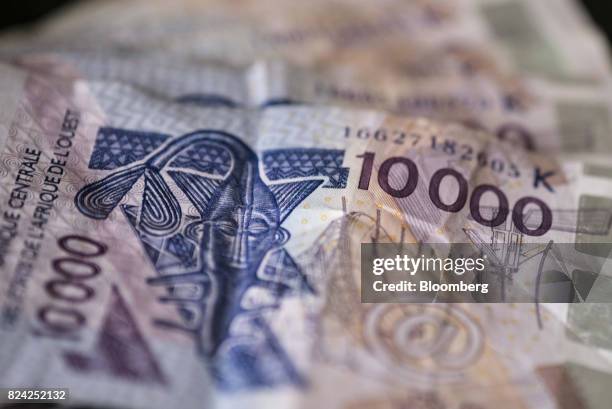 Ten thousand West African CFA franc currency banknotes sit in this arranged photograph in Dakar, Senegal, on Saturday, July 29, 2017....