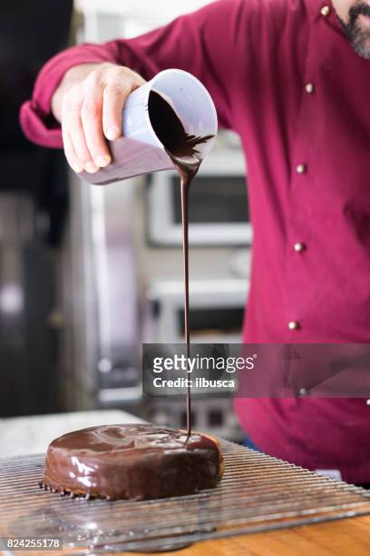 italian pastry making patisserie baking confectioner: covering sachertorte with chocolate - sachertorte stock pictures, royalty-free photos & images