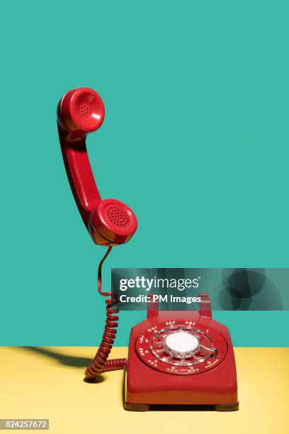 red landline phone, receiver in mid air - vintage telephone stock-fotos und bilder