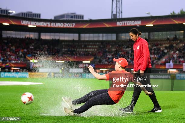 German coach Steffi Jone looks on as a volunteer slips as she tries to shoot a ball on the water sodden pitch prior to the start of the UEFA Womens...