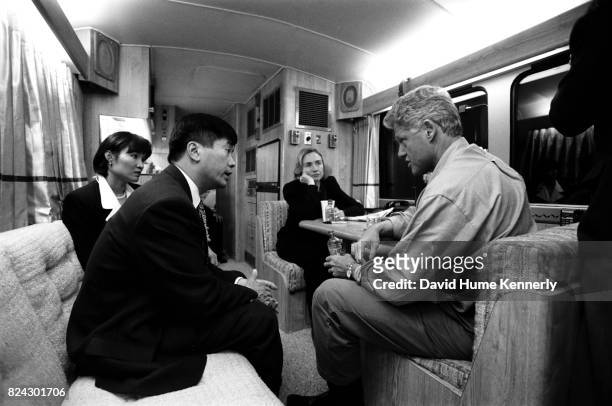 President Bill Clinton speaks with governor of Washington Gary Lock and his wife, Mona Lee, on the campaign bus while First Lady Hillary Clinton...