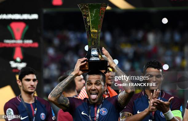 Paris Saint-Germain's Brazilian defender Dani Alves holds the trophy as he celebrates with teammates after winning the French Trophy of Champions...