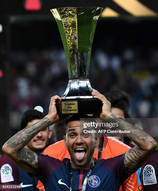 Paris Saint-Germain's Brazilian defender Dani Alves holds the trophy as he celebrates with teammates after winning the French Trophy of Champions...