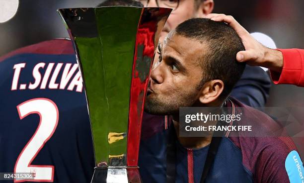 Paris Saint-Germain's Brazilian defender Dani Alves kisses the trophy as he celebrates with teammates after winning the French Trophy of Champions...