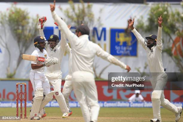 Sri Lankan cricketer Kusal Mendis looks at the umpire as Indian close-in fielders appeal for his wicket during the 4th Day's play in the 1st Test...