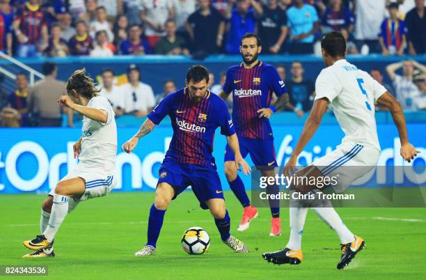 Lionel Messi of Barcelona scores against the defense of Raphael Varane and Luka Modric of Real Madrid in the first half during their International...