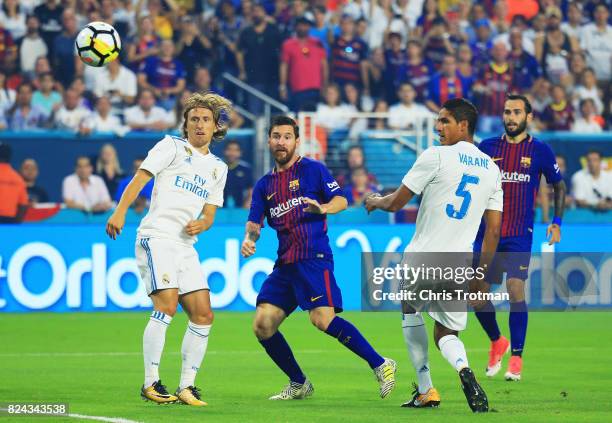 Lionel Messi of Barcelona scores against the defense of Raphael Varane and Luka Modric of Real Madrid in the first half during their International...