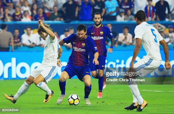 Lionel Messi of Barcelona scores against the defense of Raphael Varane and Luka Modric of Real Madrid in the first half during their International...