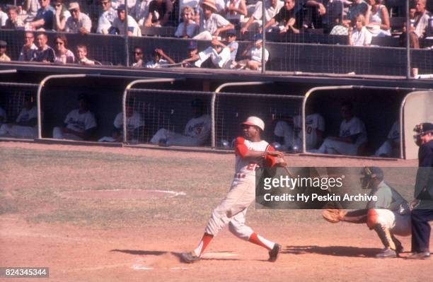 Frank Robinson of the Cincinnati Reds swings at the pitch as catcher John Roseboro of the Los Angeles Dodgers and umpire Dusty Boggess look on during...