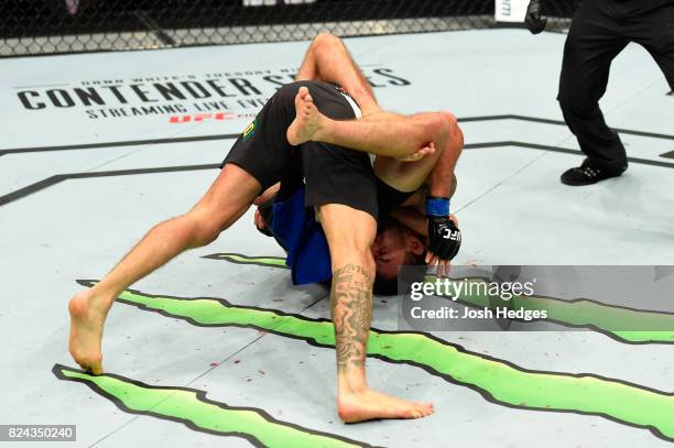 Renato Moicano of Brazil taps out against Brian Ortega after being caught in a choke hold in their featherweight bout during the UFC 214 event at...