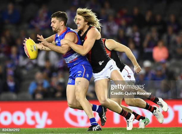 Tom Liberatore of the Bulldogs is tackled by Dyson Heppell of the Bombers during the round 19 AFL match between the Western Bulldogs and the Essendon...
