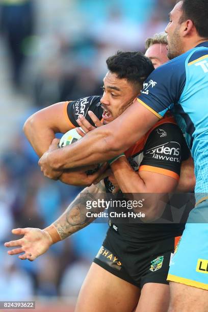 David Nofoaluma of the Titans is tackled during the round 21 NRL match between the Gold Coast Titans and the Wests Tigers at Cbus Super Stadium on...
