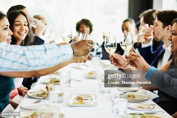 group of family and friends toasting during celebration meal in restaurant - 豪華　食事 ストックフォトと画像