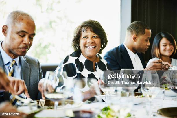 smiling mature woman sharing a meal with family in restaurant - black couple dining stockfoto's en -beelden